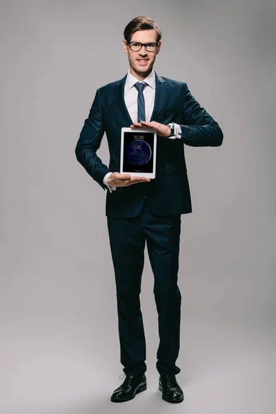 Cheerful businessman holding digital tablet with lock screen on grey background — Stock Photo