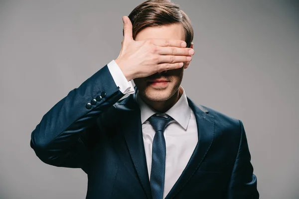 Schöner Geschäftsmann, der die Augen mit der Hand vor grauem Hintergrund bedeckt — Stockfoto