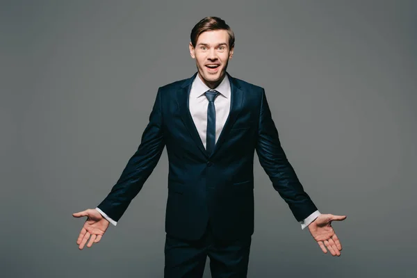 Happy businessman standing with opened arms isolated on grey — Stock Photo