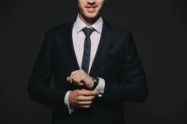Обрізаний вид бізнесмена в костюмі, зворушливий годинник ізольований на чорному — стокове фото