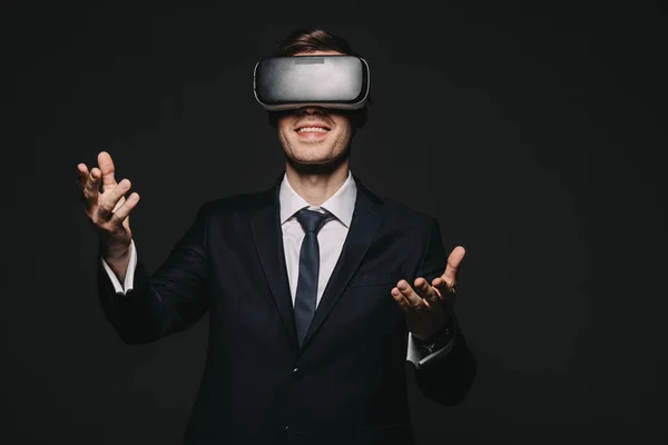 Alegre hombre de negocios en realidad virtual auriculares aislados en negro - foto de stock