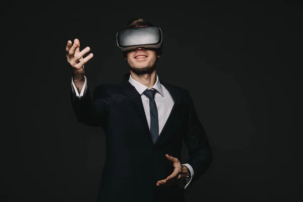 Hombre de negocios feliz en auriculares de realidad virtual aislados en negro - foto de stock