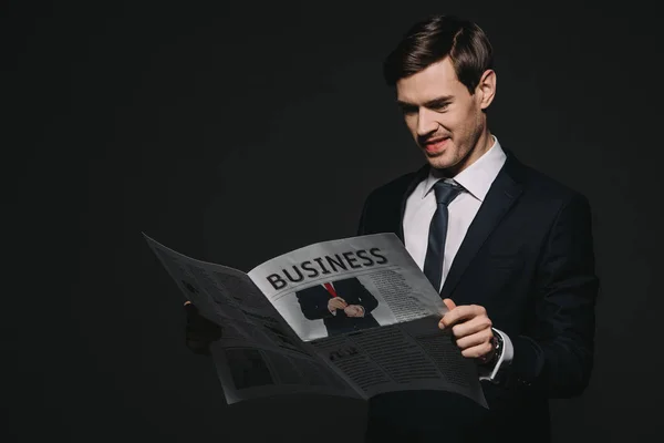 Fröhlicher Geschäftsmann liest Wirtschaftszeitung isoliert auf schwarz — Stockfoto
