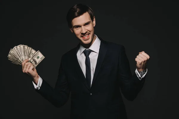 Empresário alegre segurando nota de dólar em mãos isoladas em preto — Fotografia de Stock