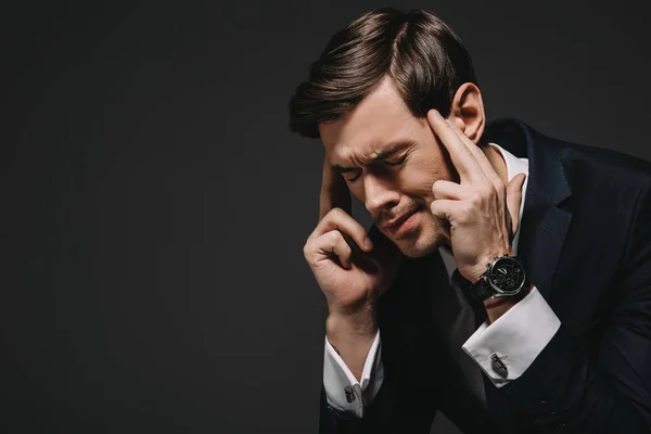 Schöner Geschäftsmann, der Schläfen berührt, während er Kopfschmerzen hat, isoliert auf schwarz — Stockfoto