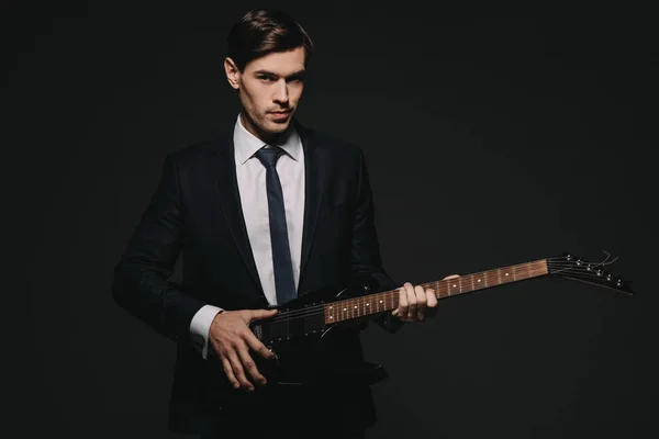 Handsome businessman playing elecrtonic guitar isolated on black — Stock Photo