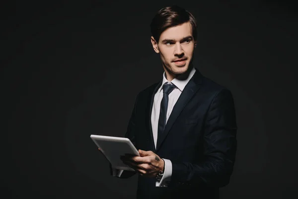 Красивий бізнесмен тримає цифровий планшет в руках ізольований на чорному — стокове фото
