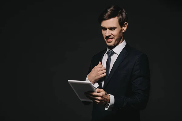 Homme d'affaires souriant tenant tablette numérique dans les mains isolées sur noir — Photo de stock