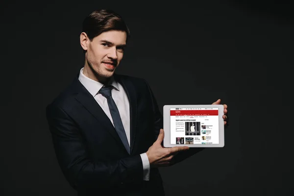 Веселий бізнесмен, тримаючись за Цифрова табличка з Бі-Бі-Новини app ізольовані на чорному екрані — стокове фото