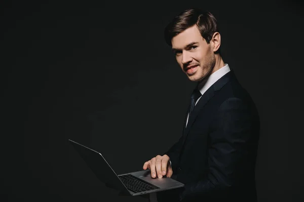 Веселий бізнесмен в костюмі, використовуючи ноутбук ізольовані на чорному — стокове фото