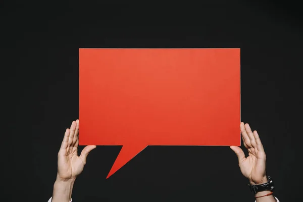 Cropped view of man holding red speech bubble in hands isolated on black — Stock Photo