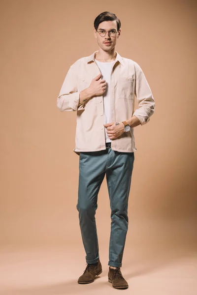 Bel homme avec montre à portée de main debout sur fond beige — Photo de stock