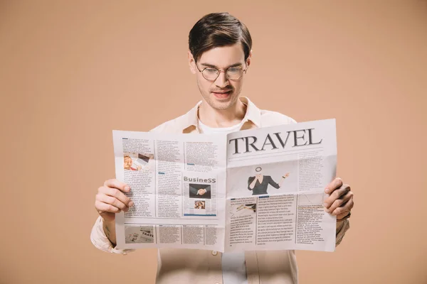 Schöner Mann mit Brille liest Reisezeitung isoliert auf beige — Stockfoto