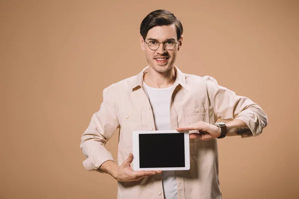 Sonriente hombre en gafas sosteniendo tableta digital con pantalla en blanco aislado en beige - foto de stock