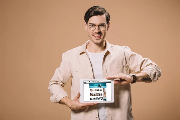 Красивый мужчина в очках с цифровой планшет с Amazon приложение на экране изолированы на бежевый — стоковое фото