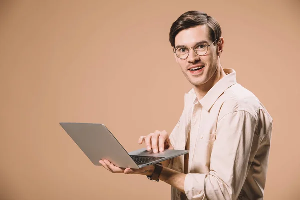 Handsome man in glasses using laptop isolated on beige — Stock Photo