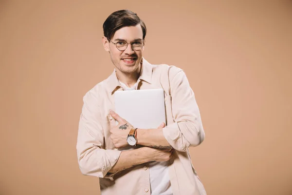 Веселий чоловік в окулярах тримає ноутбук ізольований на бежевому — стокове фото