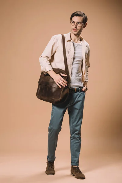 Bell'uomo in occhiali in piedi con mano in tasca su sfondo beige — Foto stock
