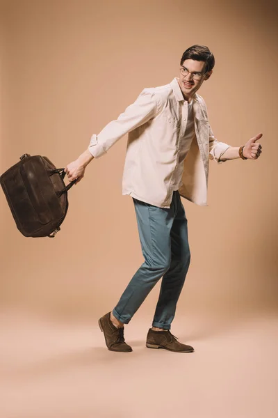 Uomo allegro in occhiali tenendo borsa marrone su sfondo beige — Foto stock