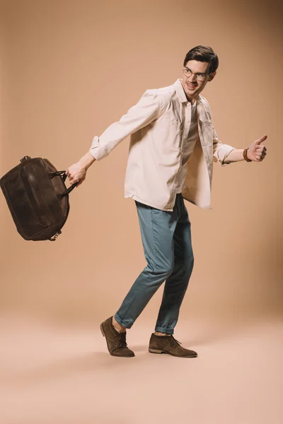 Cheerful man in glasses holding brown bag on beige background — Stock Photo