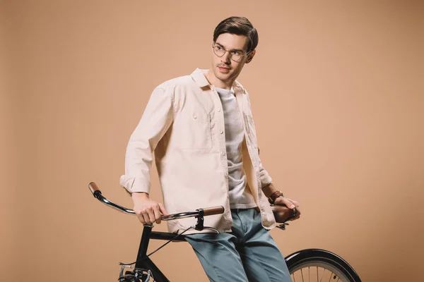 Handsome man standing near bike isolated on beige — Stock Photo