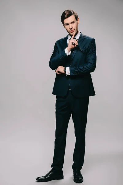 Pensativo hombre de negocios de pie en traje sobre fondo gris - foto de stock