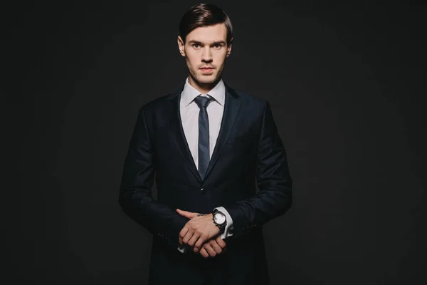 Handsome and confident man standing in suit isolated on black — Stock Photo