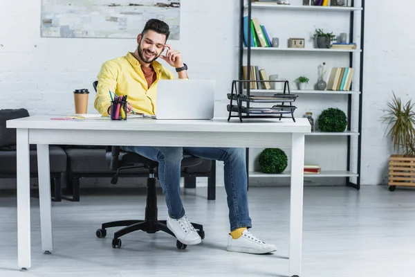 Uomo d'affari barbuto sorridente guardando lo schermo del computer portatile in ufficio moderno — Foto stock