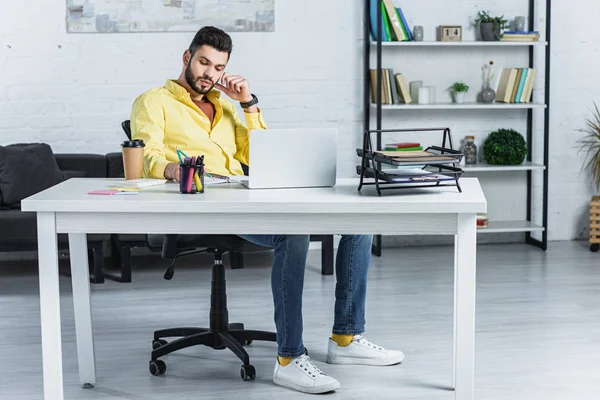Концентрированный бородатый бизнесмен в желтой рубашке работает в офисе — стоковое фото