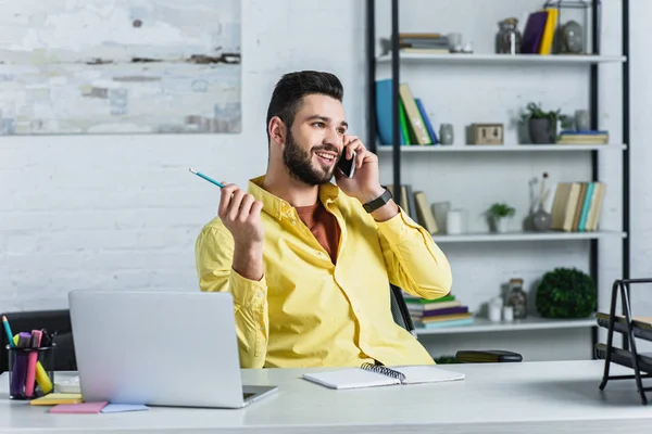 Alegre hombre de negocios barbudo hablando en smartphone y mirando hacia otro lado - foto de stock