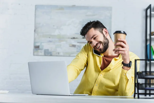 Веселый бородатый бизнесмен разговаривает на смартфоне и держит бумажную чашку — стоковое фото