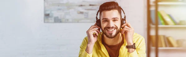 Homme d'affaires souriant dans les écouteurs regardant la caméra sur le lieu de travail — Photo de stock