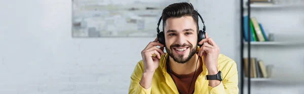 Homme d'affaires barbu joyeux dans les écouteurs regardant la caméra et souriant — Photo de stock