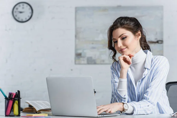Attractive businesswoman looking at laptop screen at work — Stock Photo