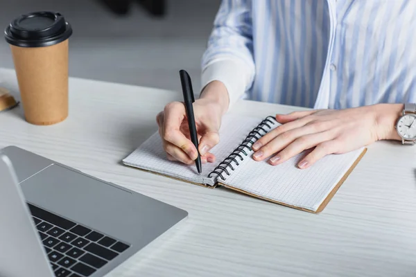 Partial view of woman writing in notebook at desk — Stock Photo