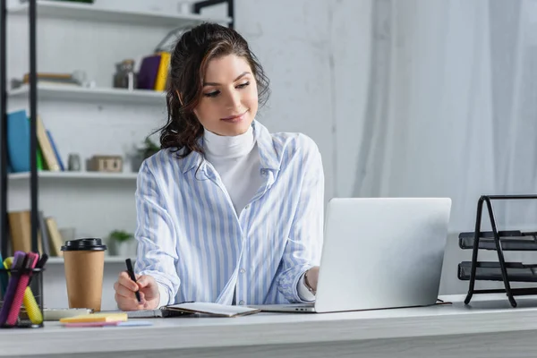 Sorrindo mulher de negócios atraente escrevendo no caderno no escritório — Fotografia de Stock