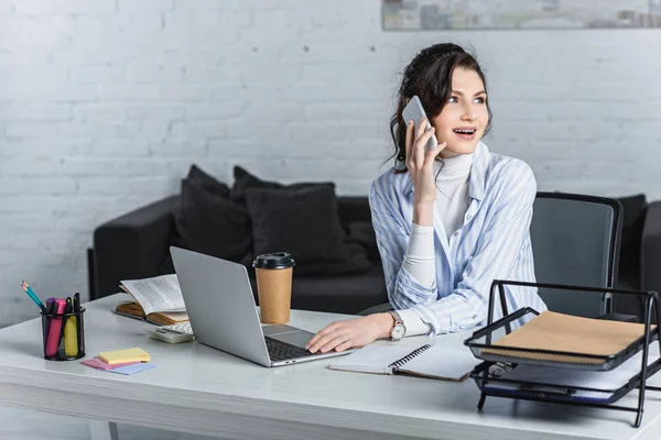 Surprised beautiful businesswoman talking on smartphone at workplace — Stock Photo