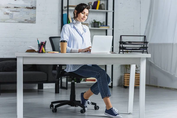 Attraktive Frau tippt auf Laptop in modernem Büro — Stockfoto