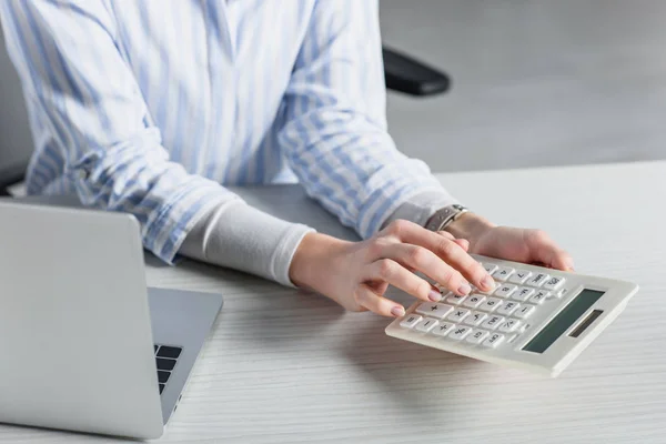 Fuoco selettivo della donna che utilizza la calcolatrice vicino al computer portatile — Foto stock