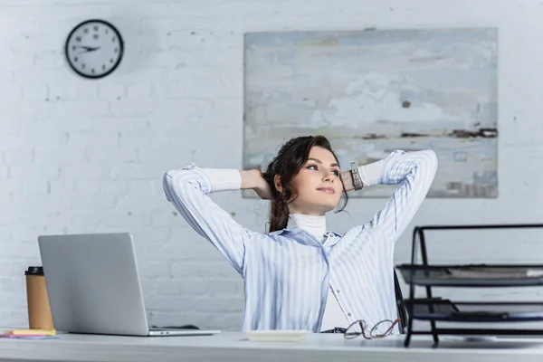Nachdenkliche Frau sitzt in modernem Büro neben Laptop — Stockfoto