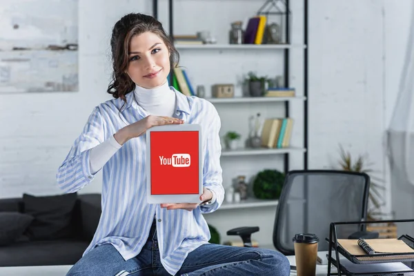 Attractive woman holding digital tablet with youtube app on screen in modern office — Stock Photo