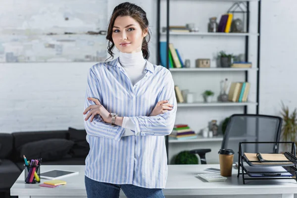 Fröhliche Frau mit verschränkten Armen in modernem Büro — Stockfoto