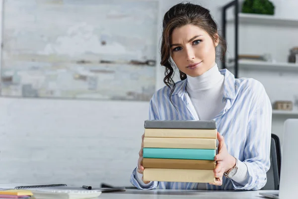 Mulher atraente segurando livros em mãos no escritório moderno — Fotografia de Stock