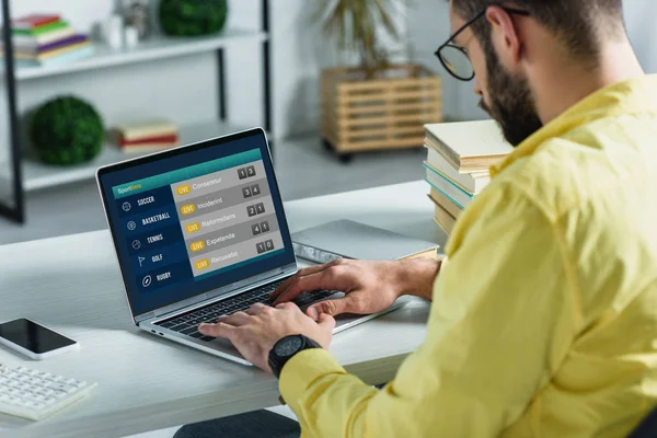 Homme barbu regardant ordinateur portable avec site de paris sportifs à l'écran dans le bureau moderne — Photo de stock