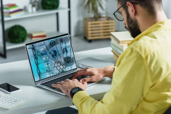 Бородатий чоловік дивиться на ноутбук з медичним веб-сайтом на екрані в сучасному офісі — стокове фото