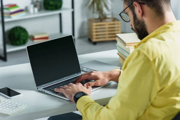 Uomo barbuto guardando computer portatile con schermo bianco in ufficio moderno — Foto stock