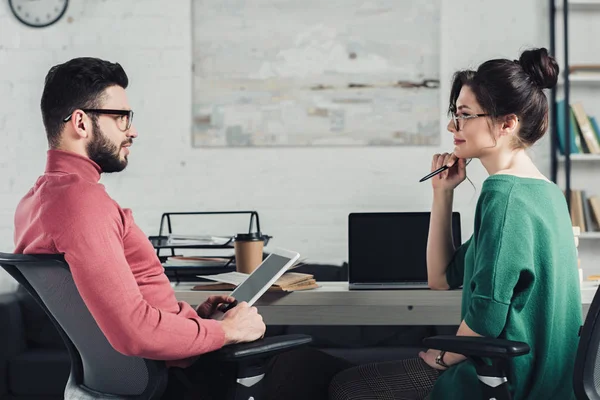 Handsome man looking at attractive colleague while holding digital tablet in hands — Stock Photo