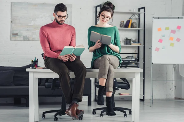 Coworkers studying with books while sitting on table in modern office — Stock Photo