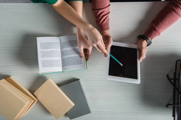 Vue du haut de la femme pointant vers la tablette numérique avec écran blanc avec crayon près des livres — Photo de stock