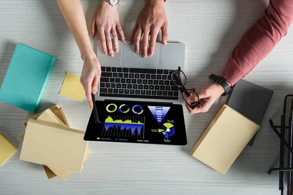Corte vista de mulher apontando para laptop com gráficos e praphs na tela perto de homem segurando óculos — Fotografia de Stock